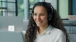 © Yuliia - Positive Hispanic business woman in headphones talking video call conference businesswoman female girl consultant help line client support agent talk virtual chat happy smiling in office communicate