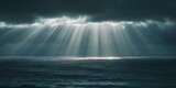 Golden sun rays breaking through dark storm clouds over deep ocean water, providing hope and a dramatic mood