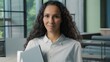 © Yuliia - Female portrait Hispanic business woman looking at camera holding laptop computer in office Arabian ethnic businesswoman female girl worker executive manager company agent posing indoors at workplace