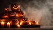 © Маргарита Вайс - Group of carved pumpkins arranged in stack with burning candles and fog. Eerie and festive concept suitable for holiday advertising, design templates and autumn campaigns