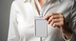 © Abimusa Gallery - Close-up of a person in a white shirt holding a blank white ID card holder with a lanyard.