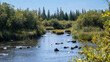 © Connect Images - Serene river flowing through lush green trees under a clear blue sky.  Hudson Bay, Churchill, Manitoba, Canada