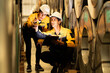 © Montri - two Industrial engineers inspecting large metal rolls in warehouse storage. Wearing safety uniforms and helmets. inventory check, manufacturing logistics, and factory teamwork. engineer, two worker.