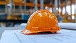 © photo for everything - Safety first on the construction site with this orange hard hat! An essential piece of PPE for a safe work environment while building with architectural blueprints.