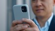 © Yuliia - Close up male hands holding mobile phone Asian middle-aged business man using cellphone chatting texting with smartphone in city Korean businessman scrolling in net online chat browsing internet work