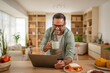 © Miljan Živković - Man working from laptop while having breakfast