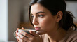 © Zhodai - A serene and pensive moment of a beautiful young woman holding a warm mug, finding comfort and reflecting by the window