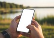© Shamim Akhtar - Person holding a smartphone outdoors near a body of water