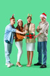 © Pixel-Shot - Group of friends with champagne and gift on green background. New Year celebration