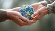 © morepiixel - Two hands hold a small globe, symbolizing unity and care for the Earth, with a blurred natural background enhancing the focus on the planet.
