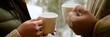 © Seventyfour - Header of woman and man holding mugs with both hands, standing close together, steam rising from cups, sharing warm drink outdoors