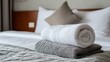 © Stock by Hemal - A High Resolution image of rolled white and grey towels stacked on a neatly made bed.