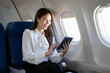 © Apichat - Woman traveling in airplane using tablet technology