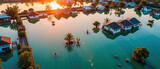 Flooded houses reflect in calm water during sunset, showcasing impact of rising water levels on residential areas