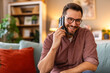 © Graphicroyalty - Man sitting on a sofa, talking on the phone, enjoying a relaxed moment at home. Combining comfort and communication, he embraces a peaceful break in his daily routine.