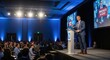 © Ciara - Confident male speaker at a business conference. Keynote presenter on stage giving a motivational presentation on leadership and innovation to a large audience in a convention hall.