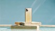 © Muhammad - A golden smartphone resting on stacked stone blocks near water against a blue sky backdrop outdoors