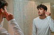 © pedro - man cleaning ear with cotton swab at bathroom