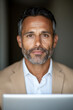 © twc - Portrait of a mature man with a stylish beard, wearing a jacket and a shirt. The background is dark. He is looking at the camera with a gentle expression.