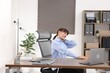 © New Africa - Young businesswoman stretching her neck at table in office