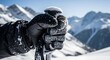 © startang141 - Close-up of a gloved hand gripping a ski pole, with snow-covered mountains visible in the background under a bright blue sky.