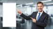 © Ada - Professional Businessman Pointing to a Blank Promotion Board. businessman smiling directly at the camera. He is pointing with his right hand to a large, blank white rectangular board or sign