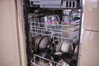© Anat art - Kitchen Dishwasher Filled With Clean Dishes, Glasses, and Utensils After a Meal in a Modern Home Setting