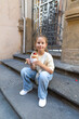 © Bogdan Pictures - A young girl sits on the sundrenched steps, delightfully savoring an irresistible ice cream treat, portraying a moment of pure joy in an enchanting urban setting full of life and color