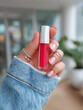 © Elena - Red lip tint in hand with rings and denim sleeve indoors