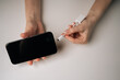 © dikushin - Top view of unrecognizable woman connecting usb flash drive to smartphone through adapter cable, facilitating data transfer and expanding mobile storage sitting on clean white table.
