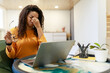 © Prostock-studio - A woman sits at her desk, rubbing her forehead in frustration. She holds her glasses in one hand and looks at her computer screen, clearly facing a challenging work task. The room is well-lit.