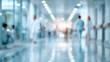 © Sabbir9003 - Blurred figures of medical professionals walking down a bright hospital corridor