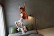 © SHOTPRIME STUDIO - Energetic young woman celebrating at home with raised arms, wearing a trendy outfit of white crop top and skirt, against a minimalist background