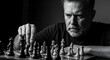 © Samsul - Monochrome portrait of a stern man concentrating as he slides a chess piece on the board with focus