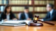 © flow art 7 - A gavel rests on a wooden desk with an open notebook, while blurred figures engage in discussion in a law office setting.