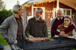 © Seventyfour - Group of middle aged Caucasian woman, middle aged Caucasian man, senior Caucasian woman and teenage Caucasian girl standing outdoors grilling food together, smiling and interacting