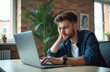 © Viktor - Young man looks tired while working on laptop computer. He feels unmotivated and distracted, staring into distance. Unproductive day with no energy for tasks.
