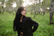© Westend61 - Woman wearing black jacket standing in birch grove with sunlight outdoors
