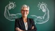 © Viktor - Smiling businesswoman with short gray hair and red glasses stands. Behind her is a chalkboard with drawings of strong arms with light bulbs. Concept idea power.