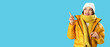 © Pixel-Shot - Young Asian woman in winter clothes pointing at something on blue background