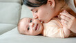 © ADDICTIVE STOCK - Mother kissing smiling baby on couch with love