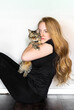 © Allison - A woman is comfortably sitting on the floor while holding a cat