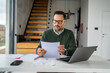 © Miljan Živković - Businessman remotely working from home office reviewing document
