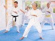 © JackF - Active mature woman wearing kimono training karate techniques in group during workout session