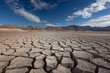 © Vitali - A vast, empty reservoir with visible cracked mud on its bed, demonstrating alarming water depletion and ecological imbalance.