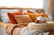 © Pixel-Shot - Wicker pouf with teapot and cups on comfortable bed in interior of bedroom, closeup