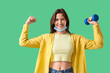 © Pixel-Shot - Young woman in medical mask with dumbbell showing muscle on green background. Immunity concept