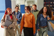 © Seventyfour - Group of multiethnic zoomers walking together in school hallway, smiling and talking, carrying backpacks and books, casual interaction