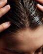 © Laongdaow Duangkaew - Close-up of hands applying nourishing scalp treatment with gentle massaging motion on parted healthy hair showing direct skin care for hair health and wellness routine concept