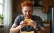 © zhao - Redhead man enjoying while eating sandwich in the morning at home. High quality